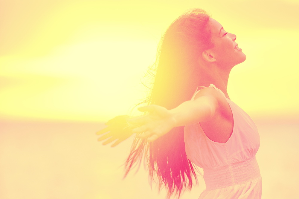 Happiness - Free happy woman enjoying sunset. Beautiful woman in white dress embracing the golden sunshine glow of sunset with arms outspread and face raised in sky enjoying peace, serenity in nature